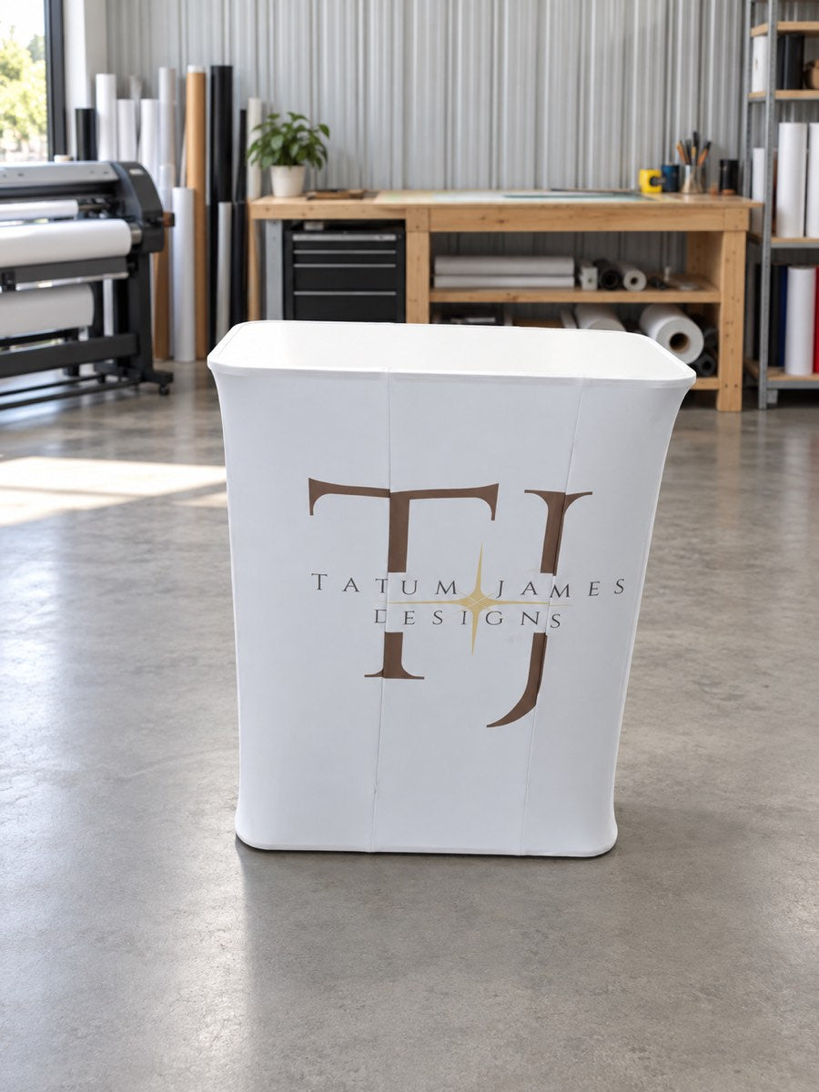 Tatum James Designs custom-printed fabric exhibition counter with white tabletop in a digitally staged workshop